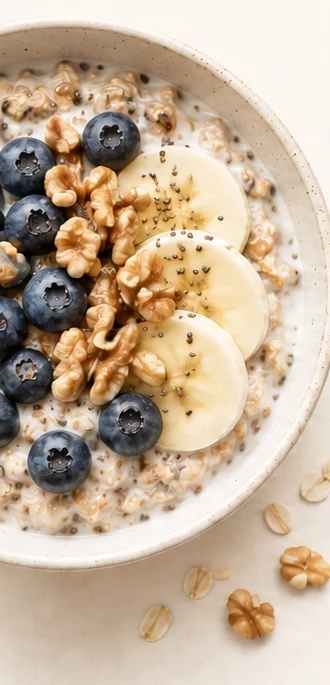 A bowl of oatmeal with blueberries, banana slices and walnuts